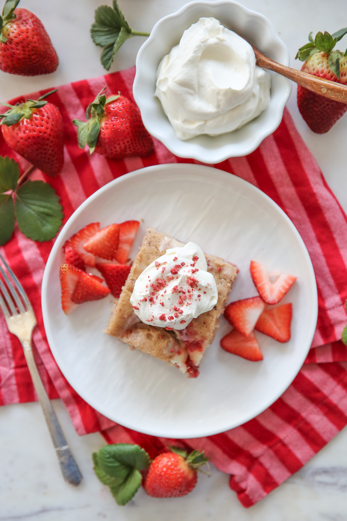 Strawberry Cheesecake Swirl Cake on a white plate with berries and cream