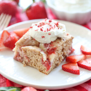 slice of strawberry swirl cake on a plate with fresh berries