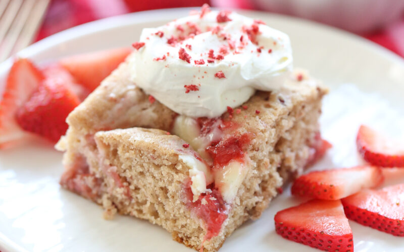 slice of strawberry swirl cake on a plate with fresh berries