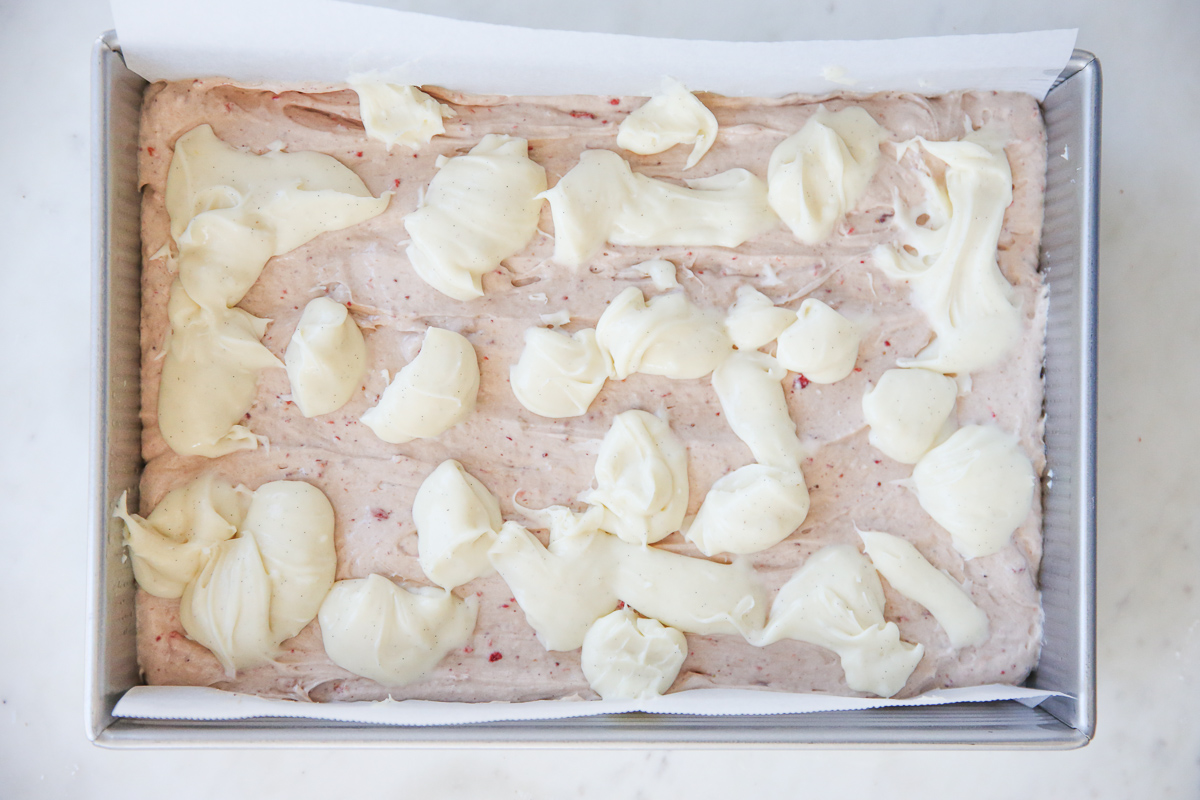 cake batter in a cake pan swirled with cheesecake batter ready to be baked