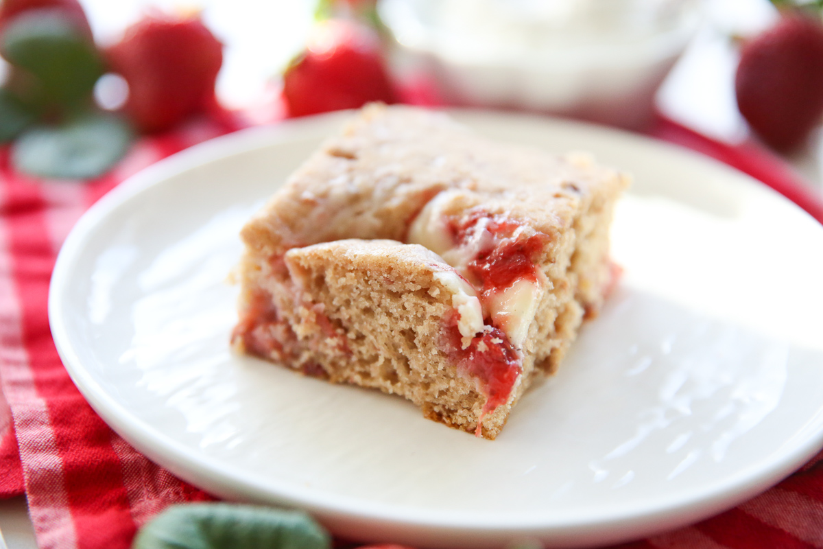 sliced strawberry cheesecake swirled cake on a white plate