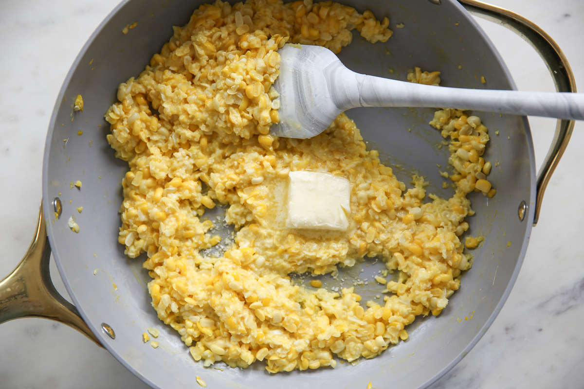 adding butter to cooked corn in a skillet