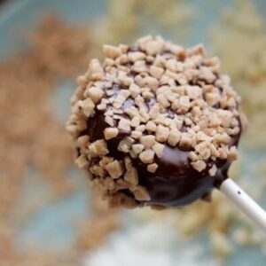 A frozen round of kiwi, completely covered in chocolate and dipped in toffee pieces.