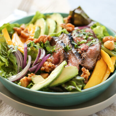 salad bowl with sliced steak and fresh mangoes